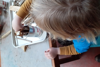 Child putting hollow sticks into a can