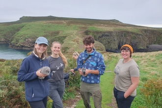 4 young people on Young Birders' Week. Two of them are holding Manx Shearwater chicks.