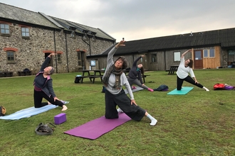 Four people do a yoga position in the courtyard on Skomer