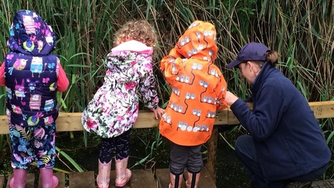Wildlife Officer shows three small children a pond