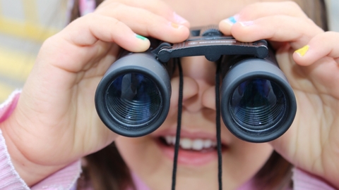 young girl looking through binoculars