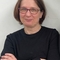 Karen Owen, a woman with glasses and short brown hair smiling in a dark blue jumper. 