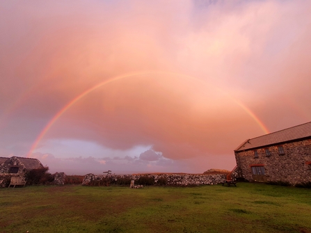 Rainbow in a pink sky. Hostel building can be seen below.