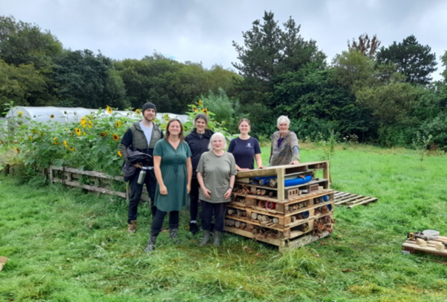 Four volunteers and two staff members standing next to their newly built insect hotel