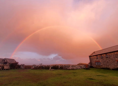 Rainbow in a pink sky. Hostel building can be seen below.